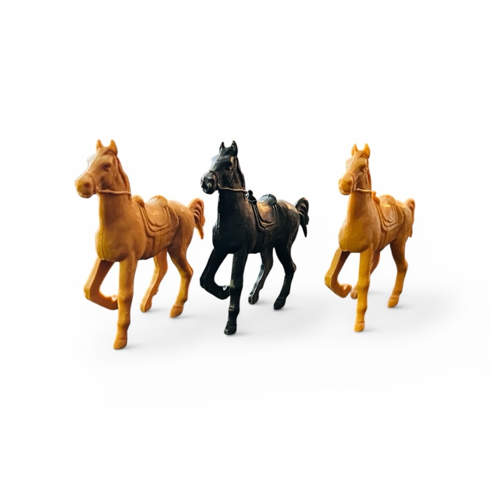 Vintage plastic toy horses with saddles, likely from the 1960s-1970s.